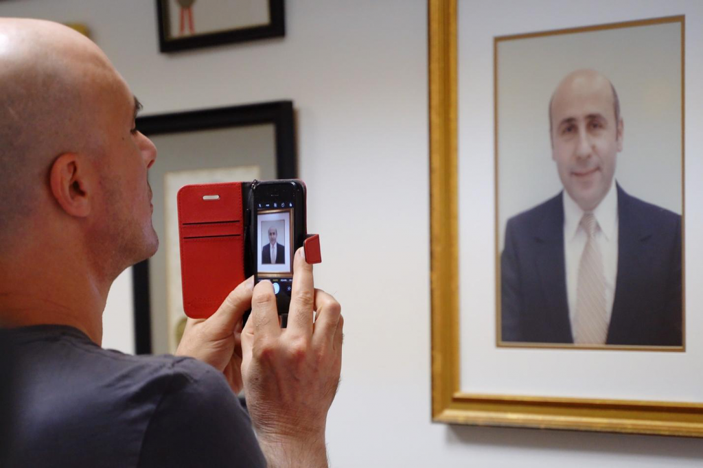 David Sheen uses phone to take a photo of a portrait of Alex Odeh.